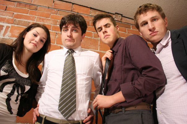 Millie, Zephyr, Bob and Rick stand in a row in front of a brick wall.